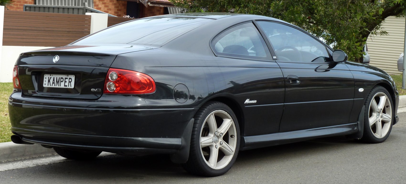 Rear side view of black sports coupe with distinctive alloy wheels.