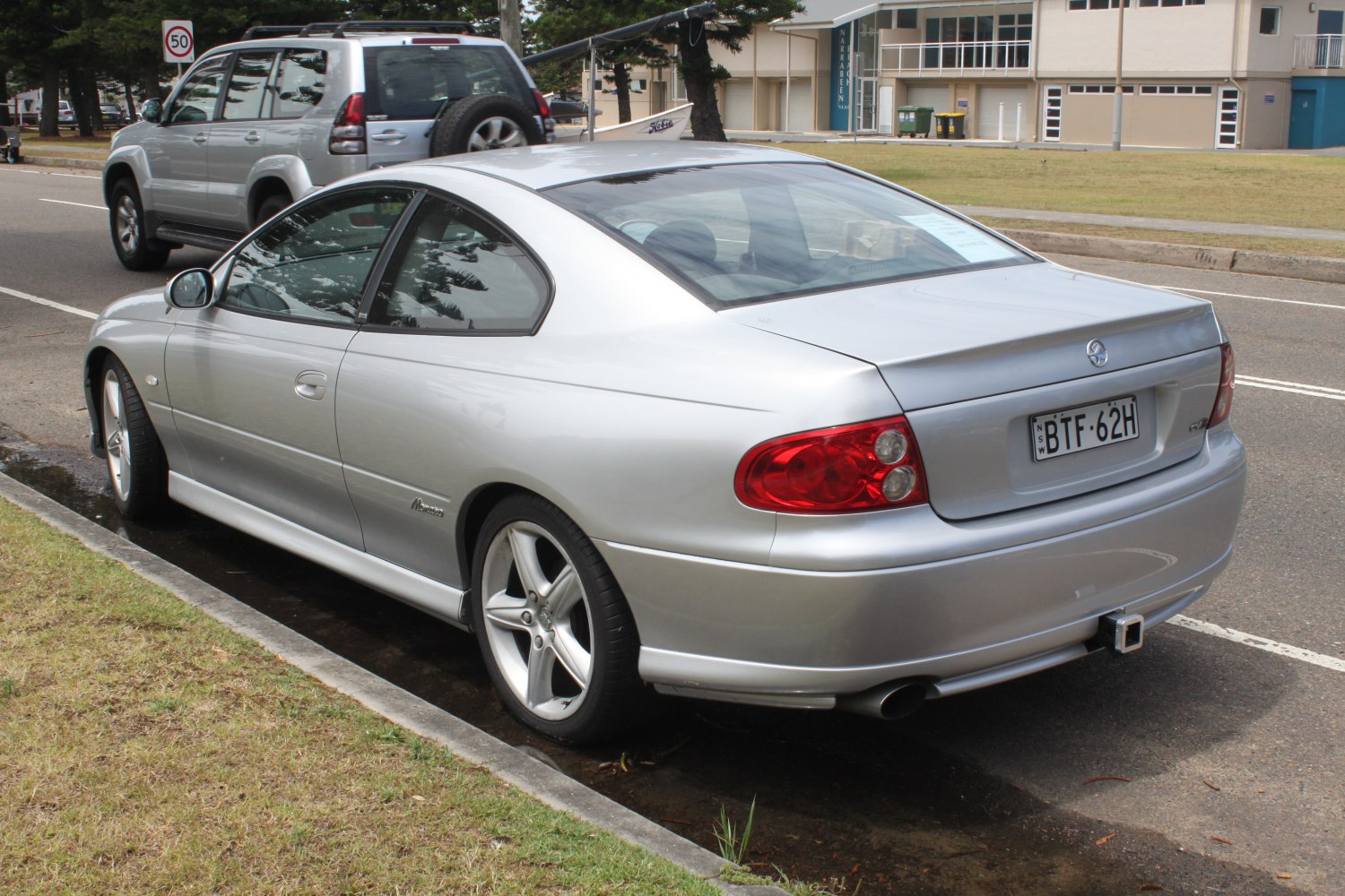 Silver two-door coupe rear-side view with red taillights and alloy wheels