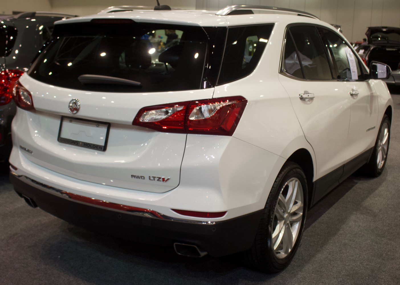 Rear and side profile view of white SUV with AWD and LTZ V badging