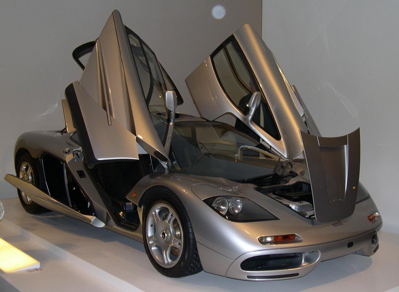 Butterfly doors open with front hood lifted on a silver 1990s supercar
