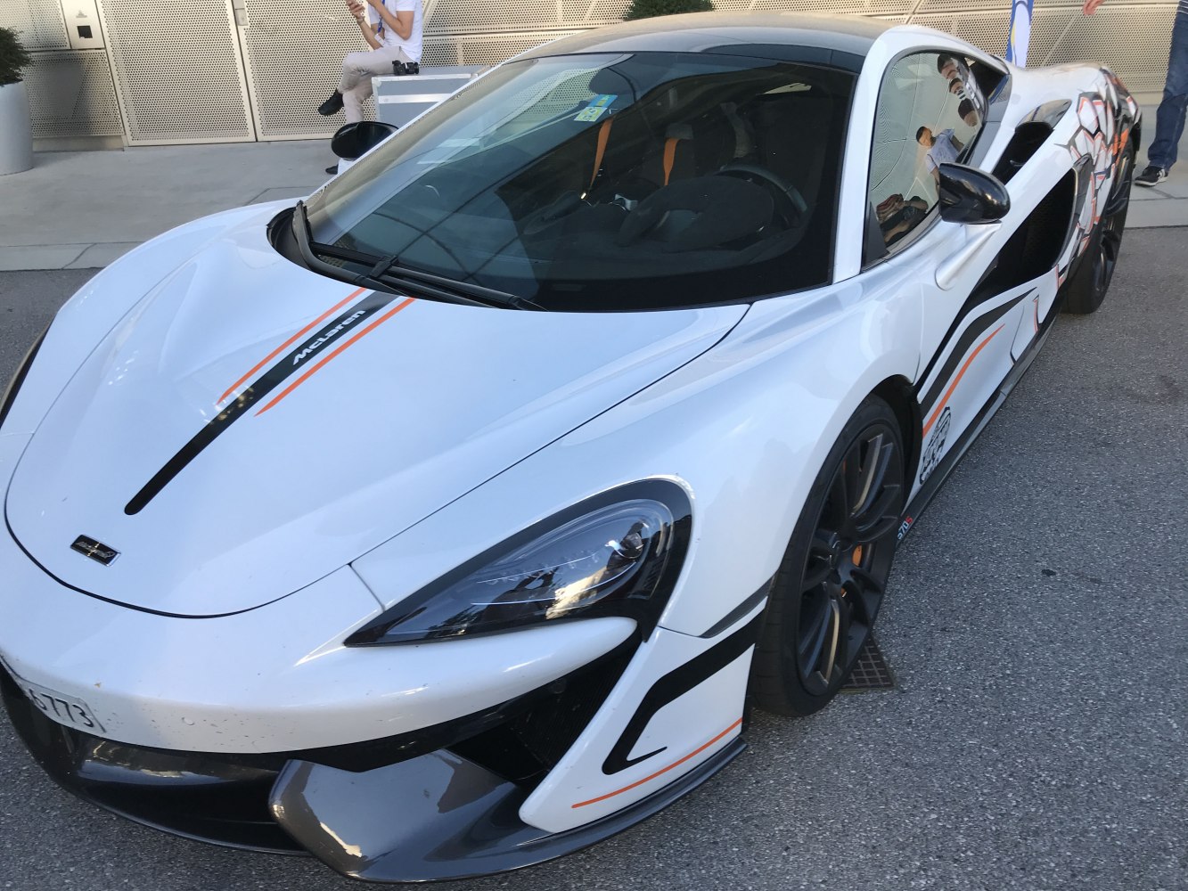 White sports car with black and orange racing stripes and aerodynamic front design