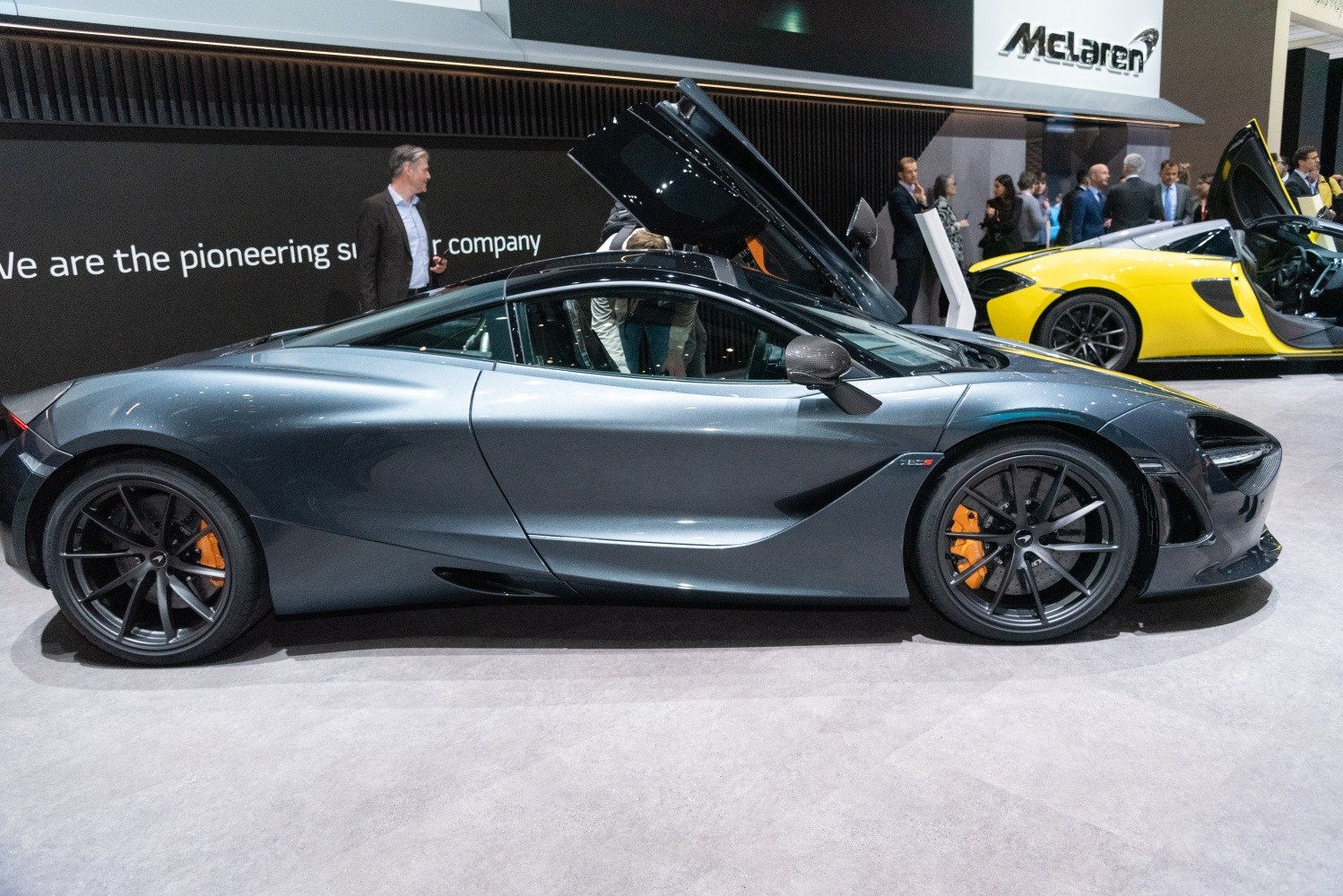 Sports car side profile with dihedral doors open, aerodynamic design, orange brake calipers