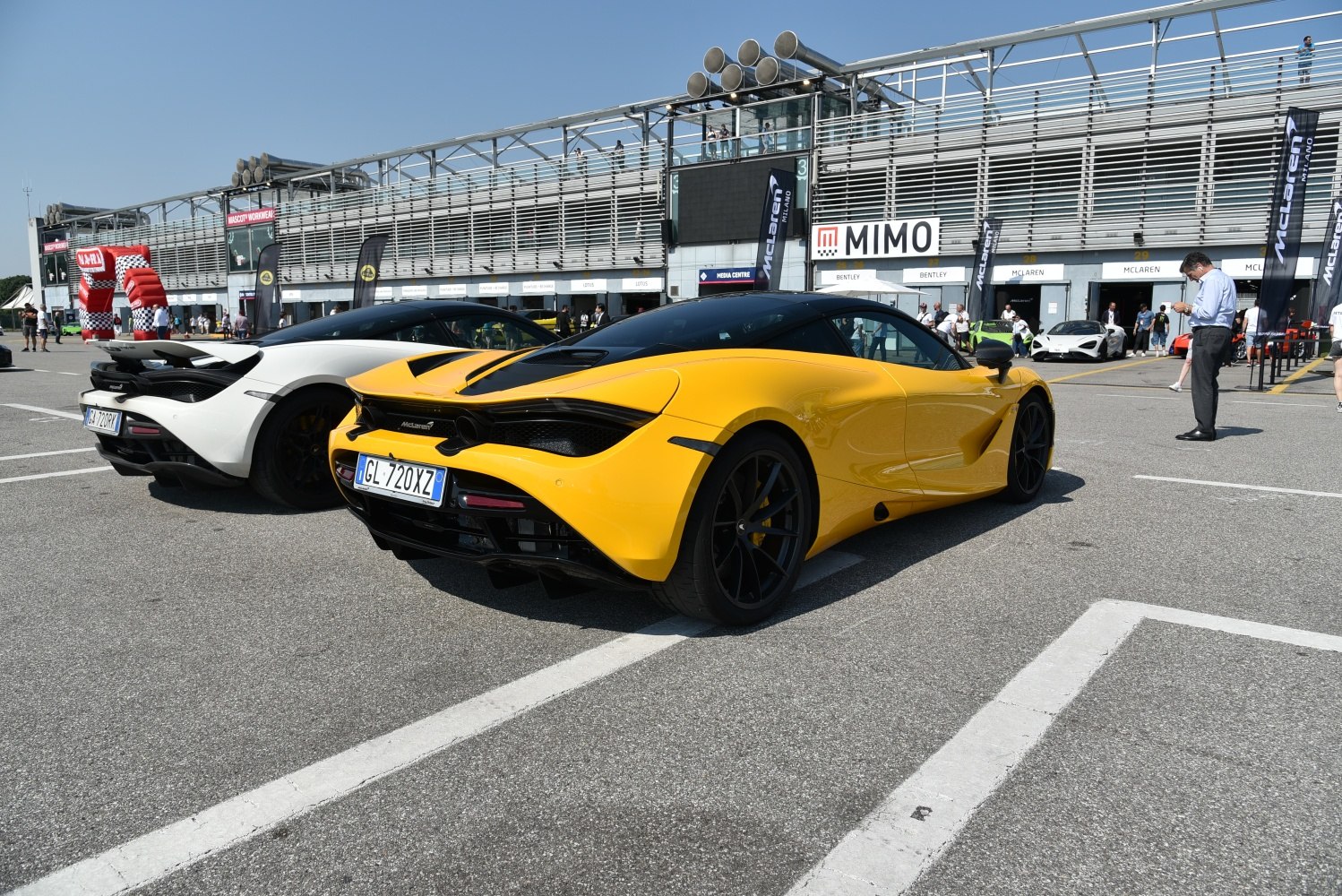 Rear view of yellow and white high-performance sports cars with aerodynamic design and distinct taillights.