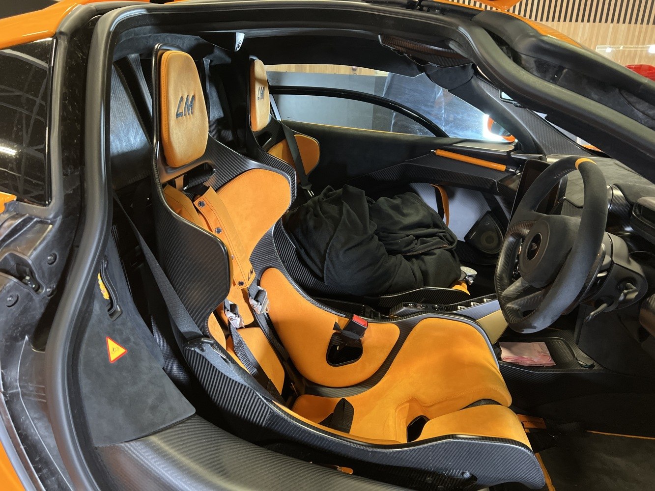 Carbon fiber racing seats with orange upholstery inside a sports car interior