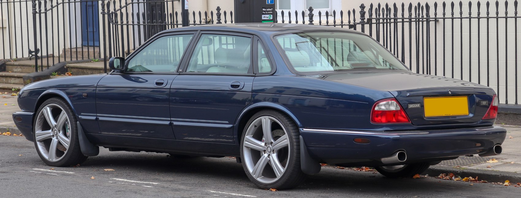 Rear-side view of luxury sedan with alloy wheels and V8 badge
