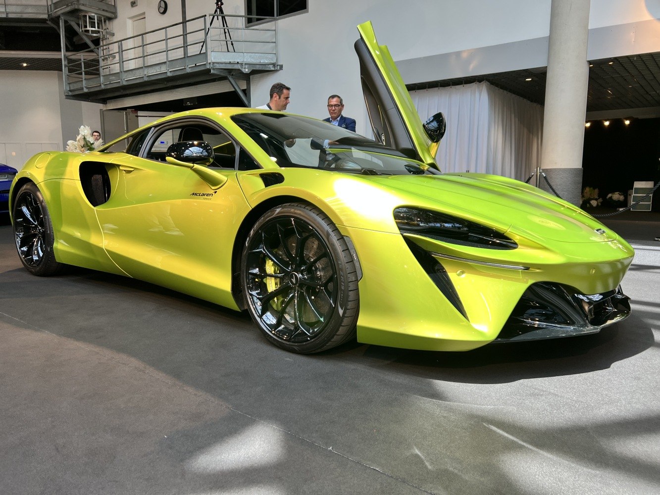 Sleek green sports car with dihedral doors and aerodynamic front design