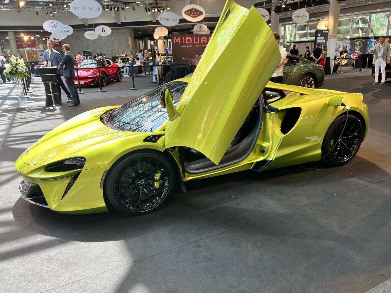 Bright yellow supercar with butterfly doors open and plugged in for charging
