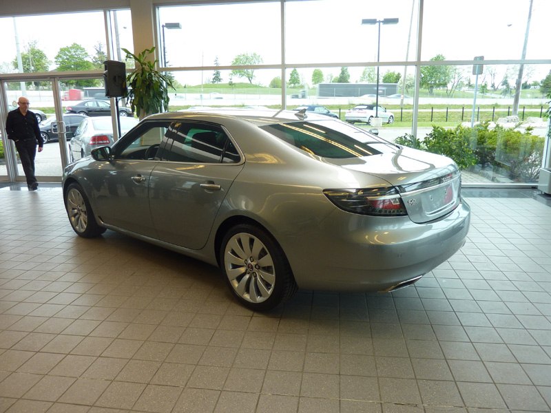 Silver sedan rear side view with multi-spoke wheels in showroom