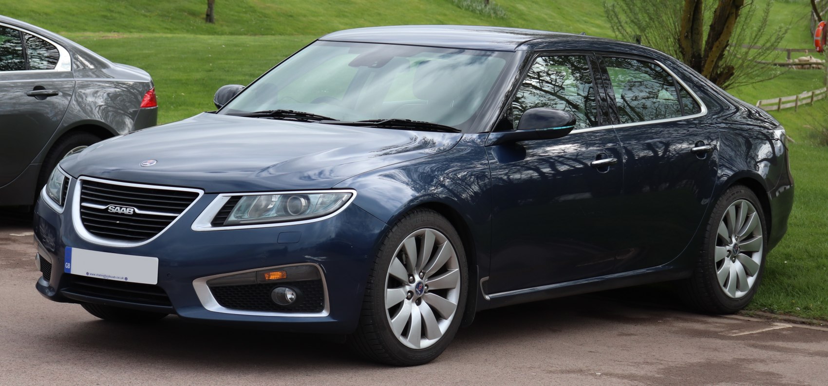 Dark blue sedan front side with grille, headlights, alloy wheels