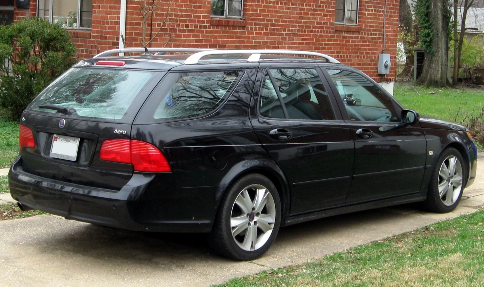 Rear and side view of a black station wagon with roof rails and distinctive taillights