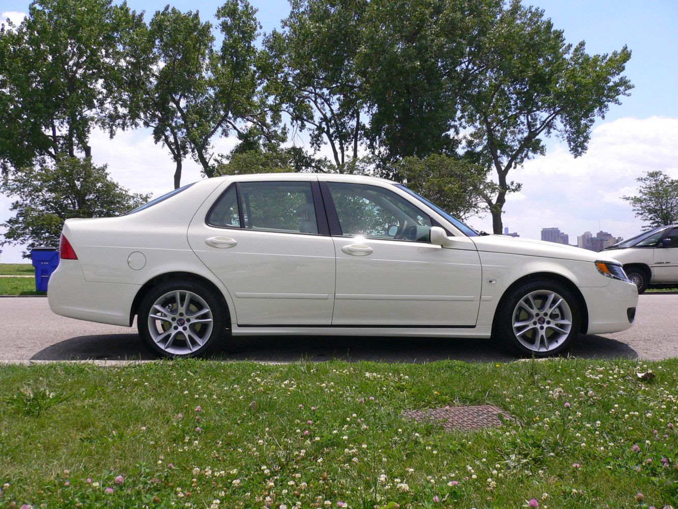 Side profile of a white sedan with alloy wheels and aerodynamic shape.