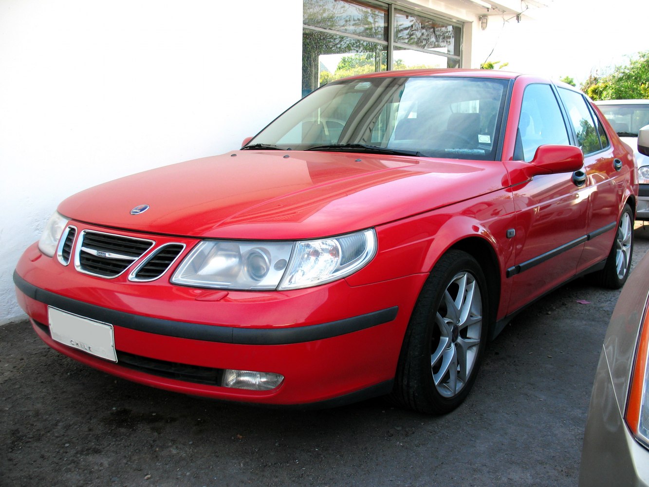 Red sedan front and side view with distinctive grille and headlights
