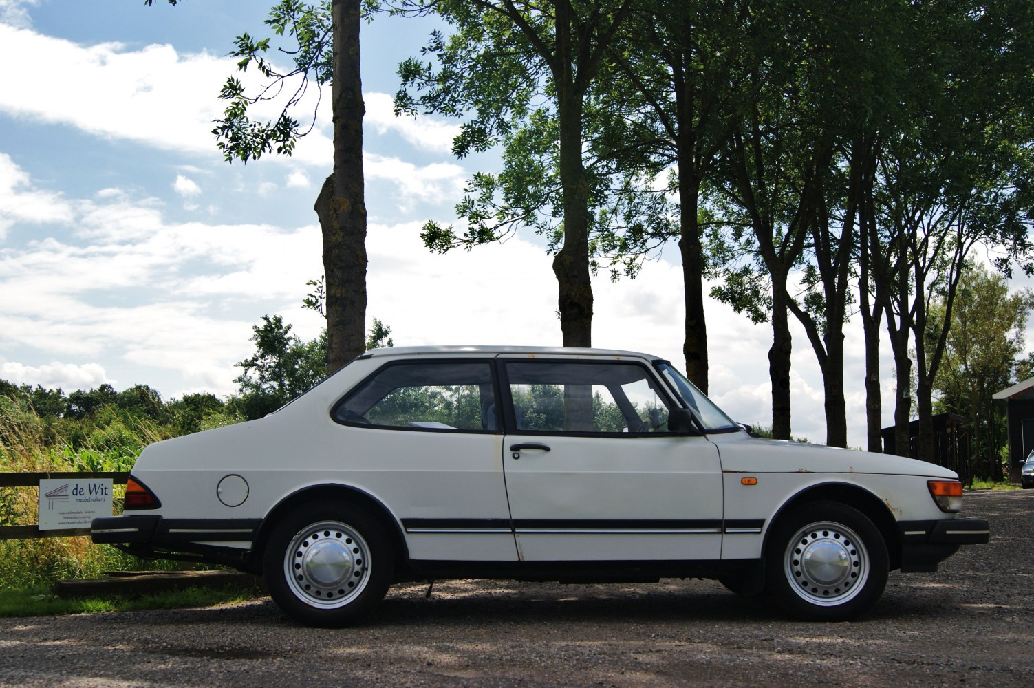 Side profile of 1980s two-door sedan with round metal wheel covers
