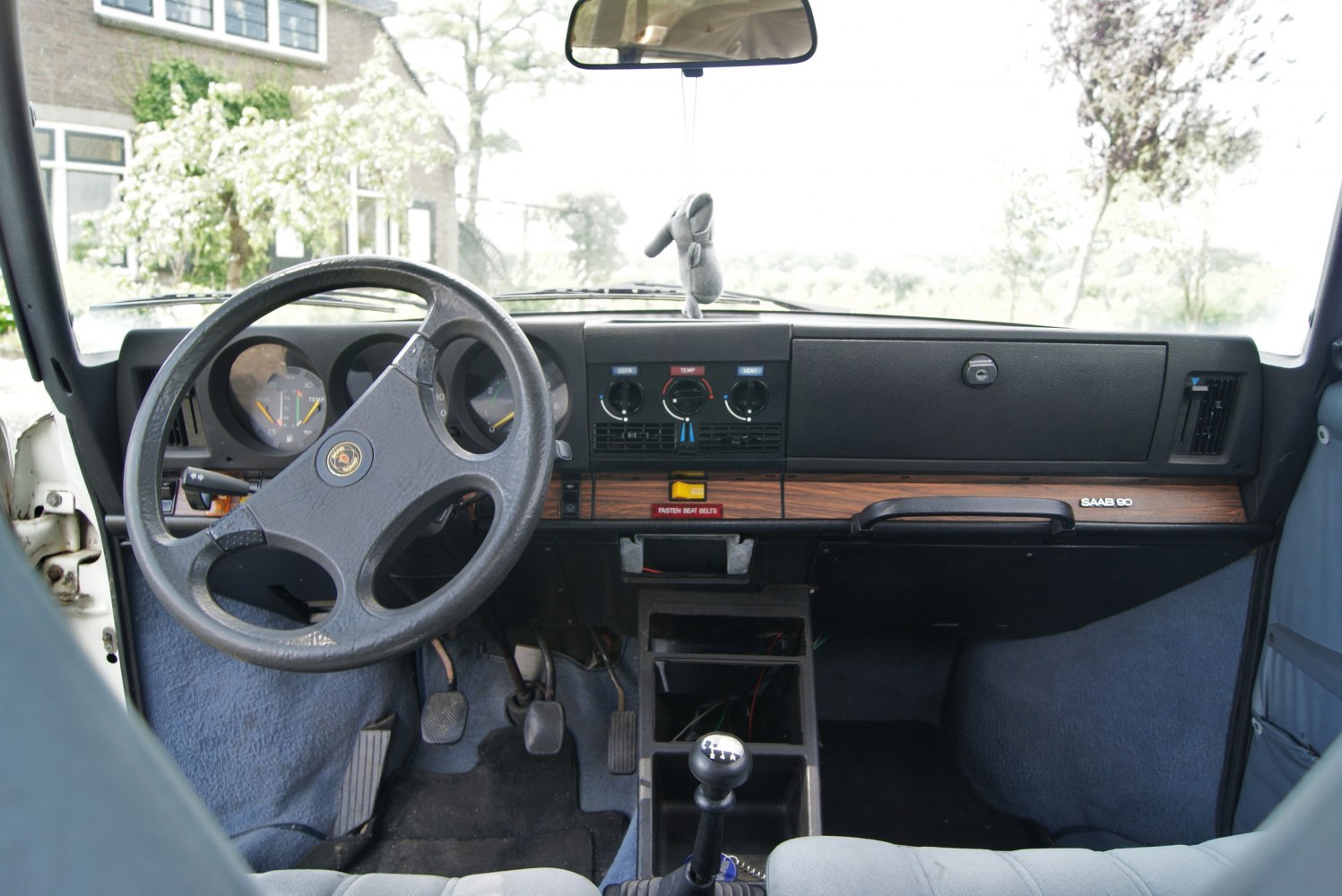 Manual gear shift, wooden dashboard, analog gauges, retro steering wheel.