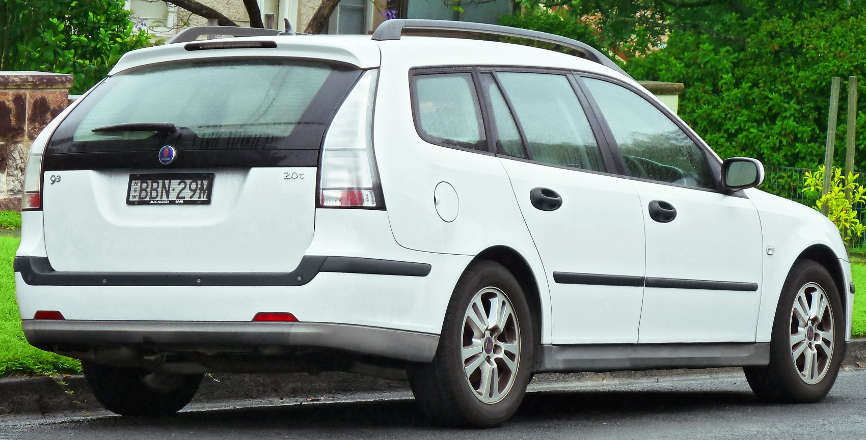 Rear view of a white station wagon with roof rails and distinct tail lights