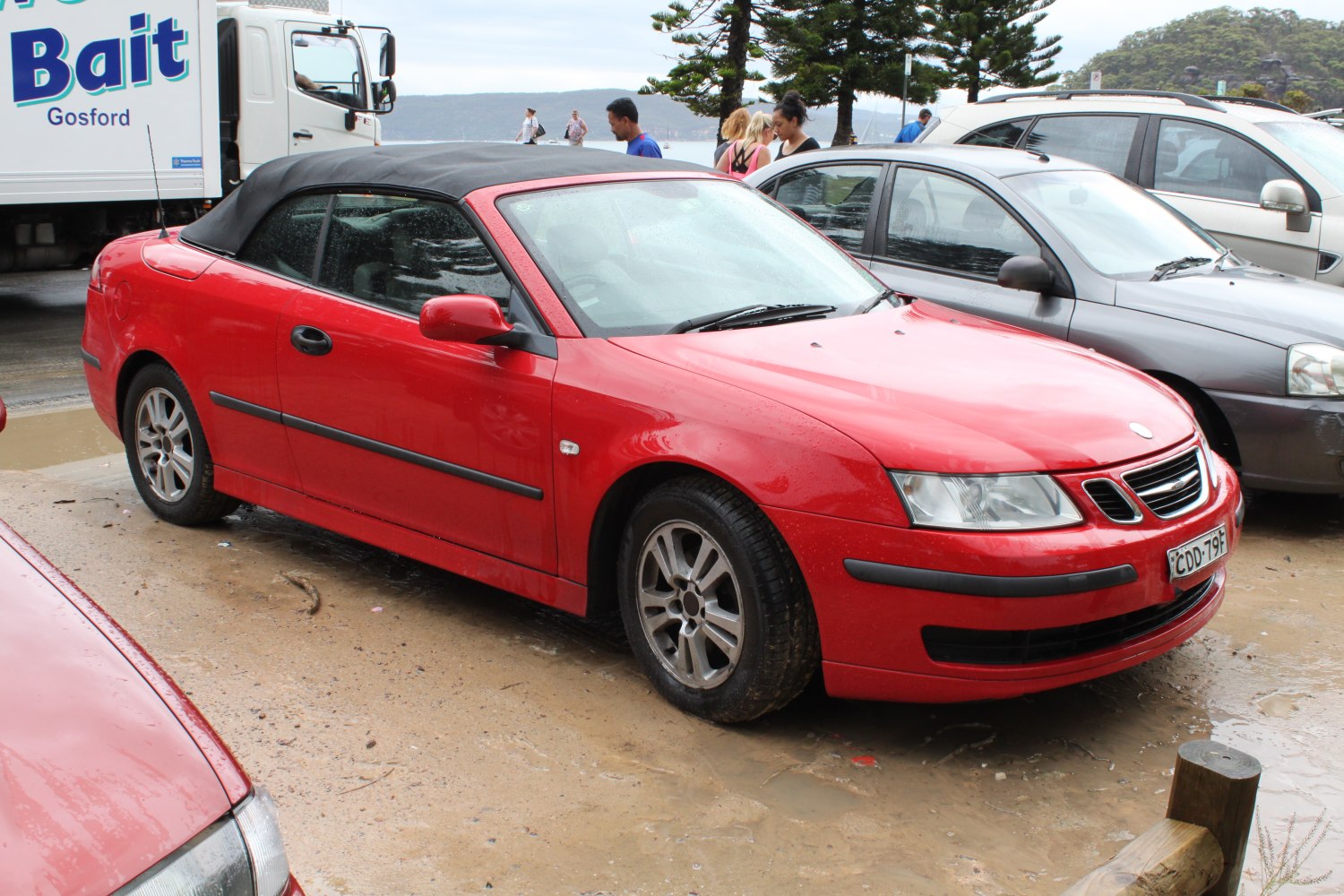 Red compact convertible with black soft top and alloy wheels