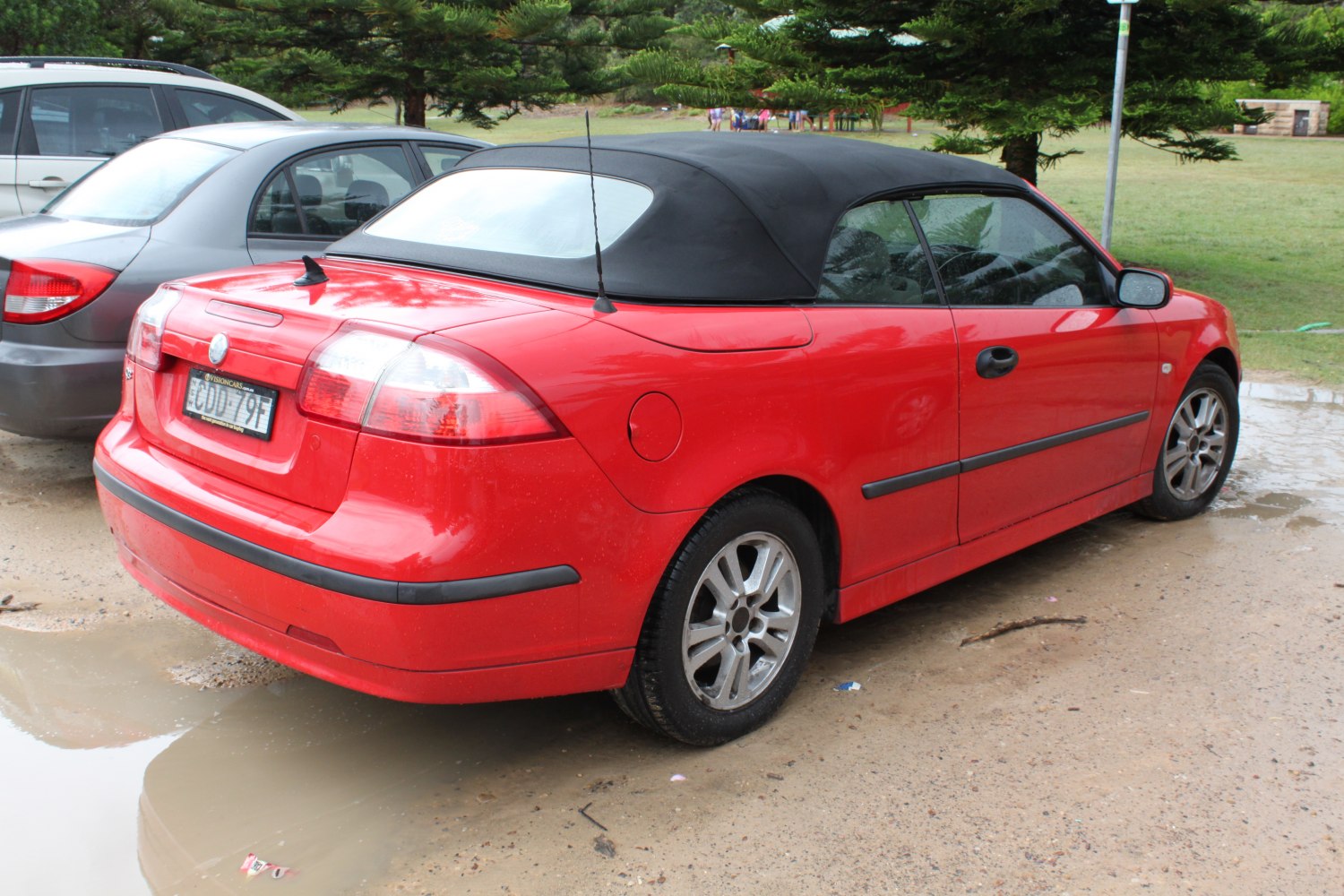 Red convertible with black soft top, rear angle, alloy wheels, distinct taillights