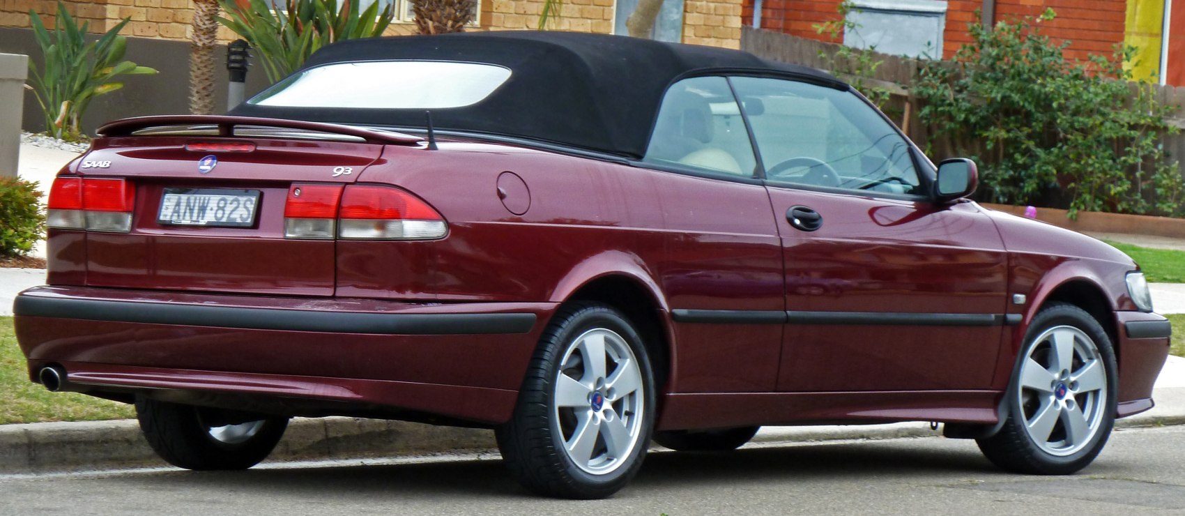 Rear and side view of convertible with black fabric soft top and alloy wheels.