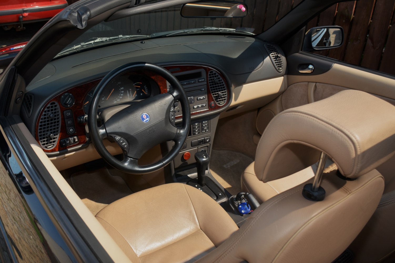 Beige leather seats and wooden dashboard interior of convertible.