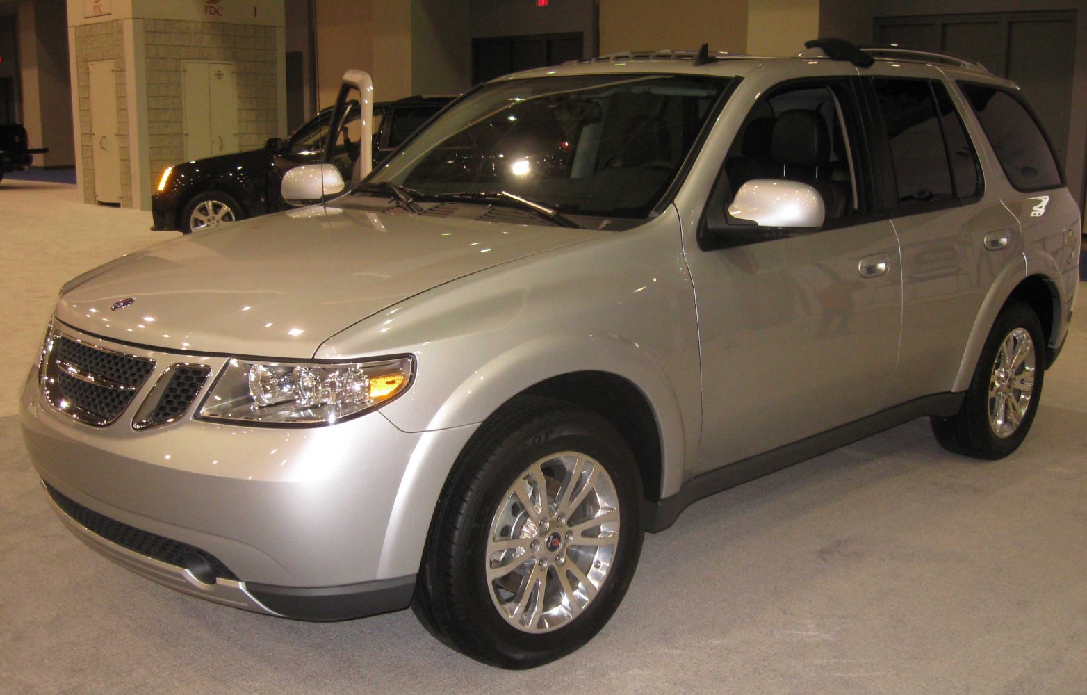 Front side view of silver SUV with headlights and chrome wheels