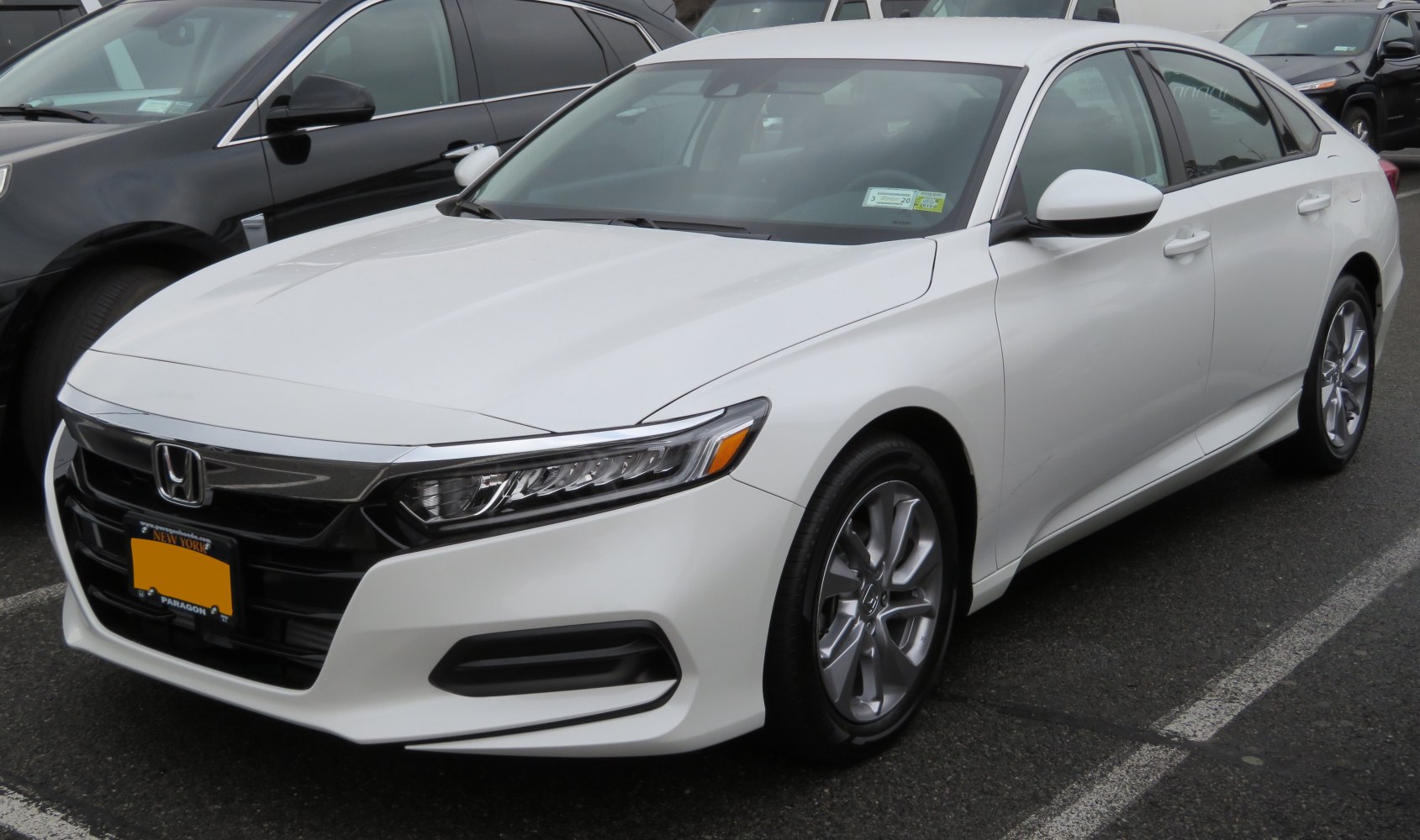 Front and side view of a white sedan with LED headlights and aerodynamic styling.