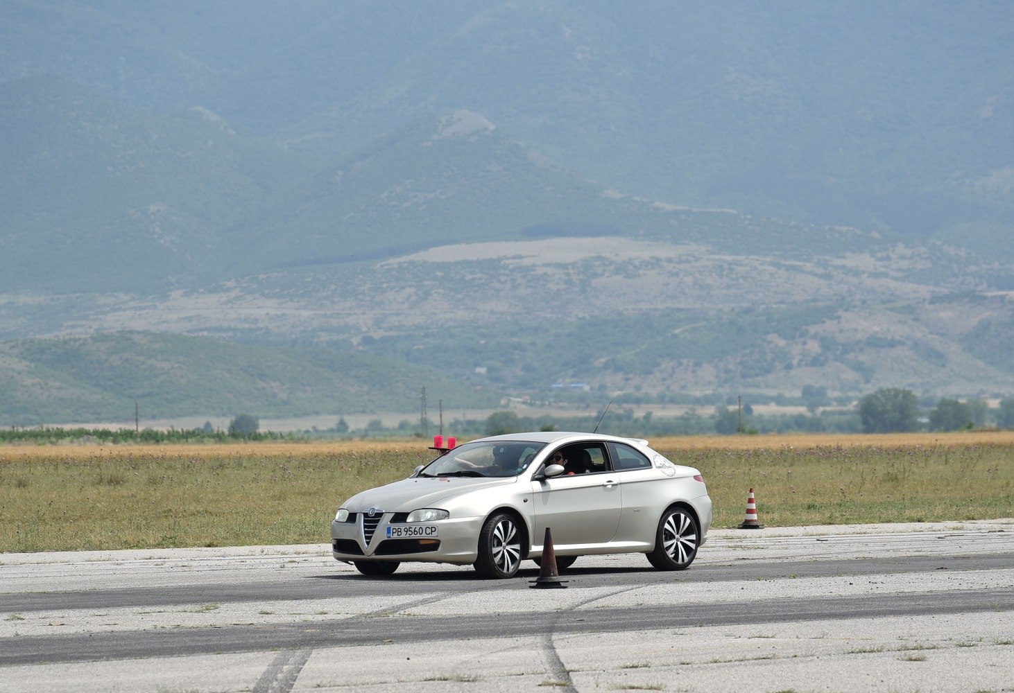 Silver sporty coupe driving on closed track with cones
