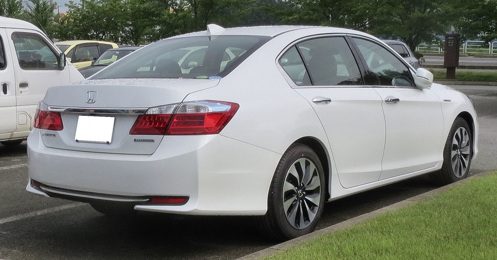 Rear and side view of white sedan with hybrid badging and alloy wheels