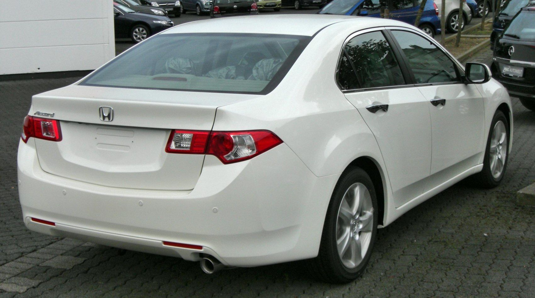 Rear and side view of white sedan with alloy wheels and distinct taillights