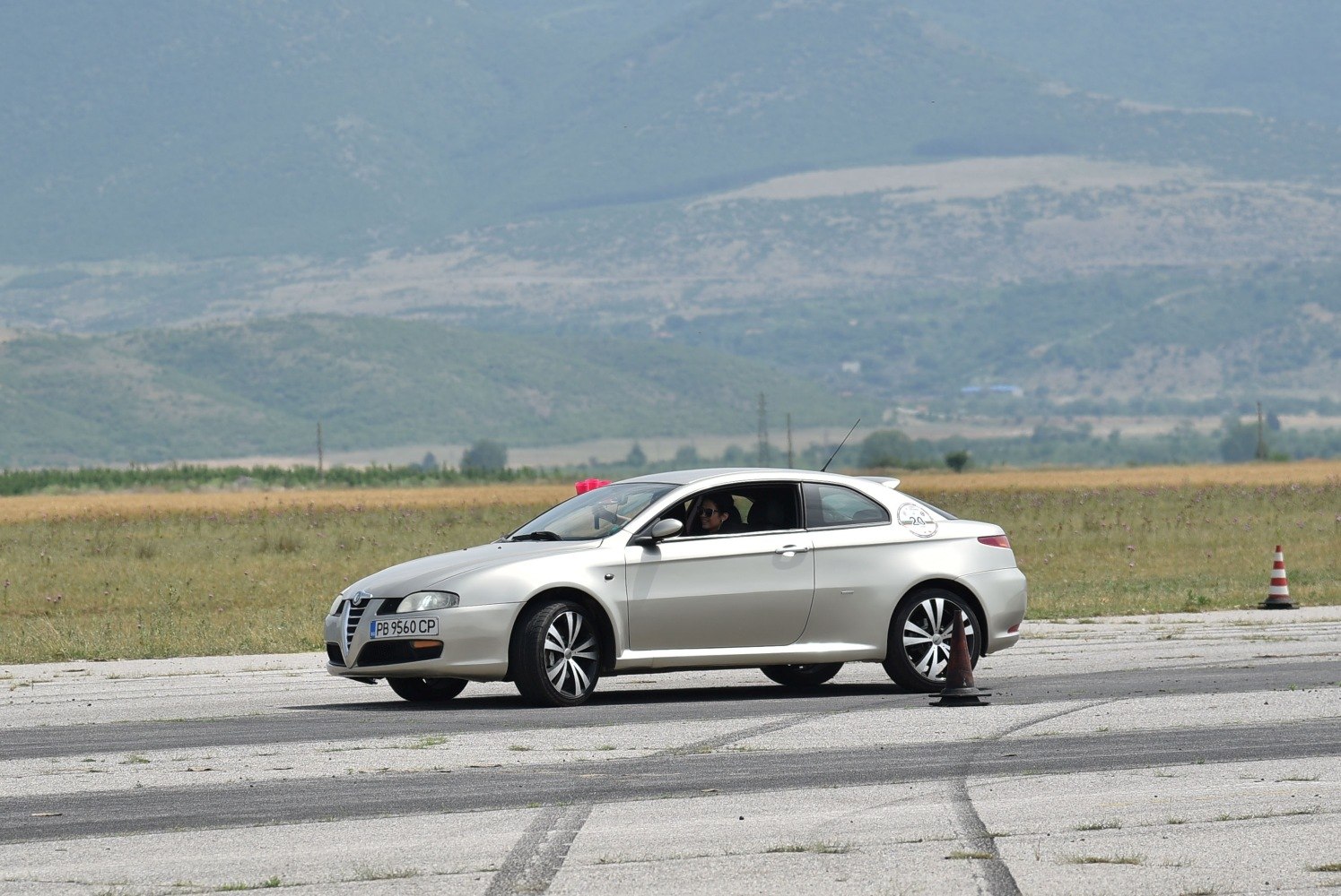 Silver coupe maneuvering on test track with traffic cones