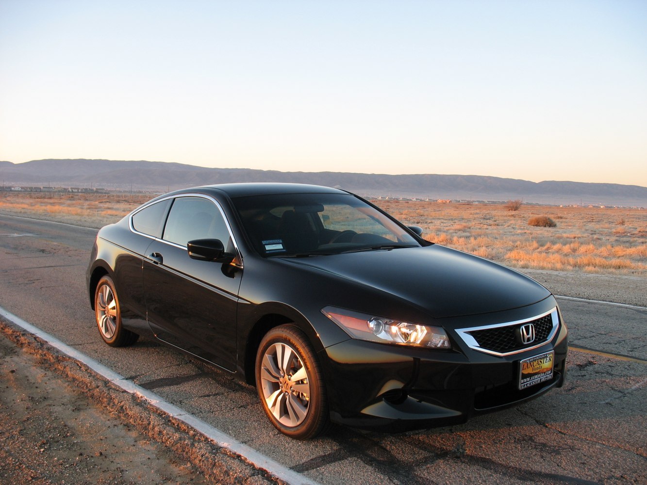 Front side view of a black two-door coupe with sleek headlights and grille