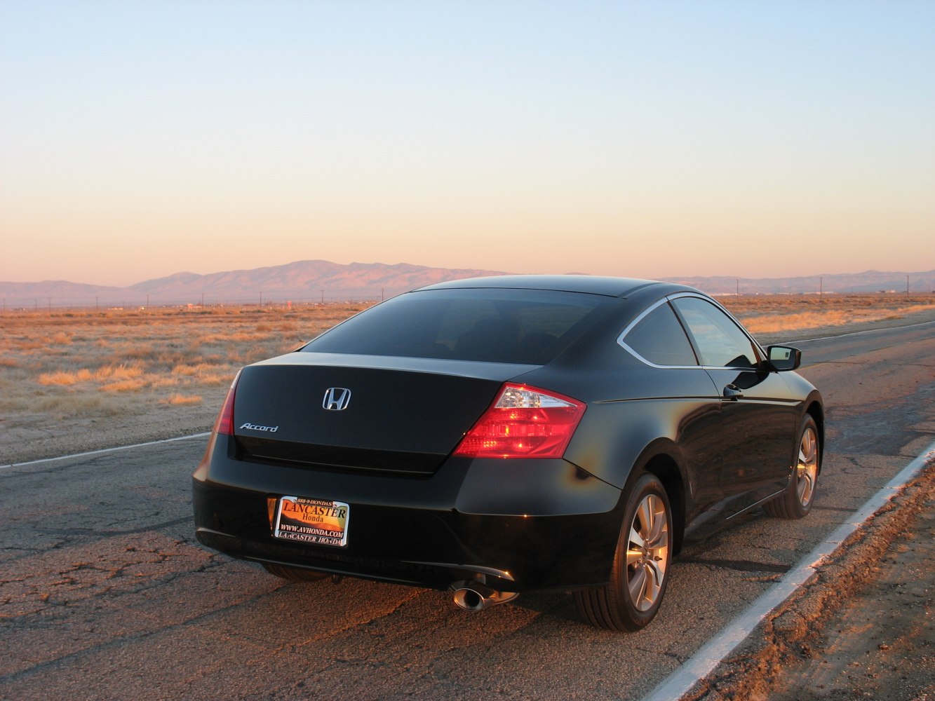Rear view of black coupe with distinctive taillights and tinted windows