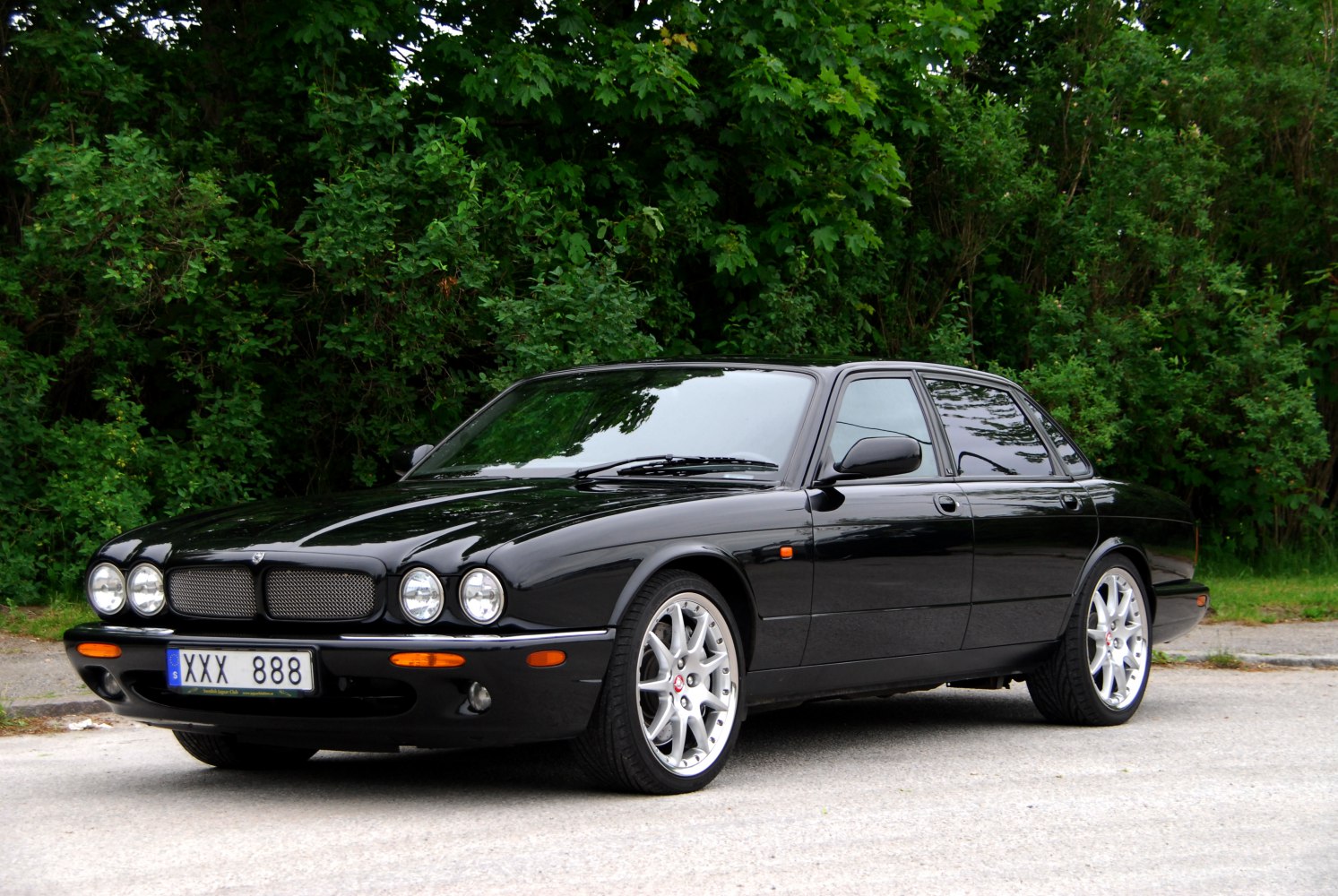 Luxury black sedan with quad round headlights and alloy wheels