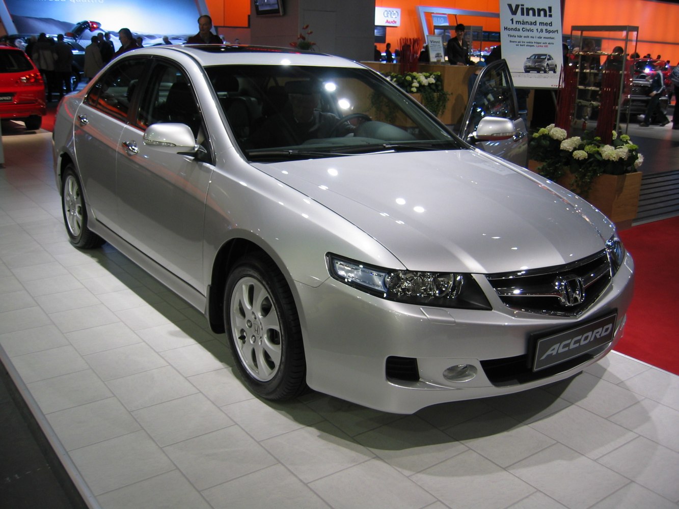 Silver sedan front three-quarter view with sharp headlights and alloy wheels