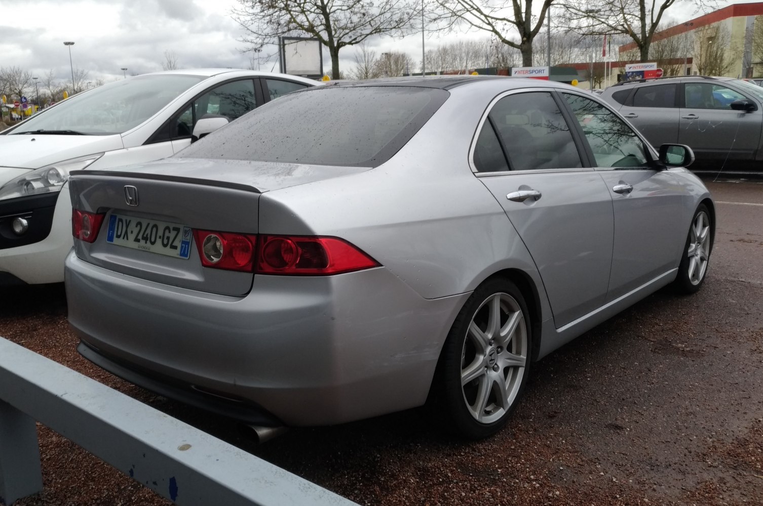 Silver sedan with rear spoiler and alloy wheels parked in a lot