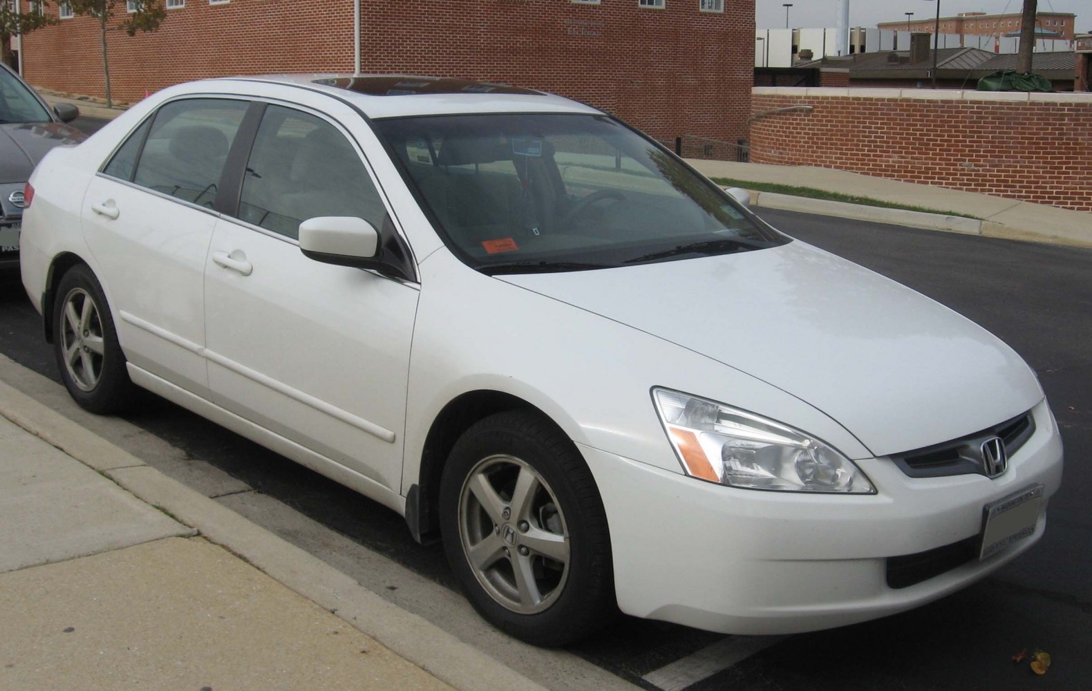 White sedan with sunroof and alloy wheels parked on street curb