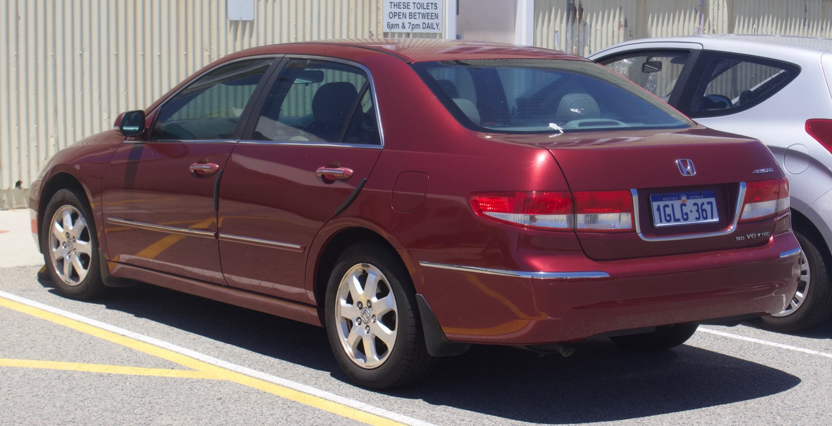 Rear side view of a maroon sedan with alloy wheels