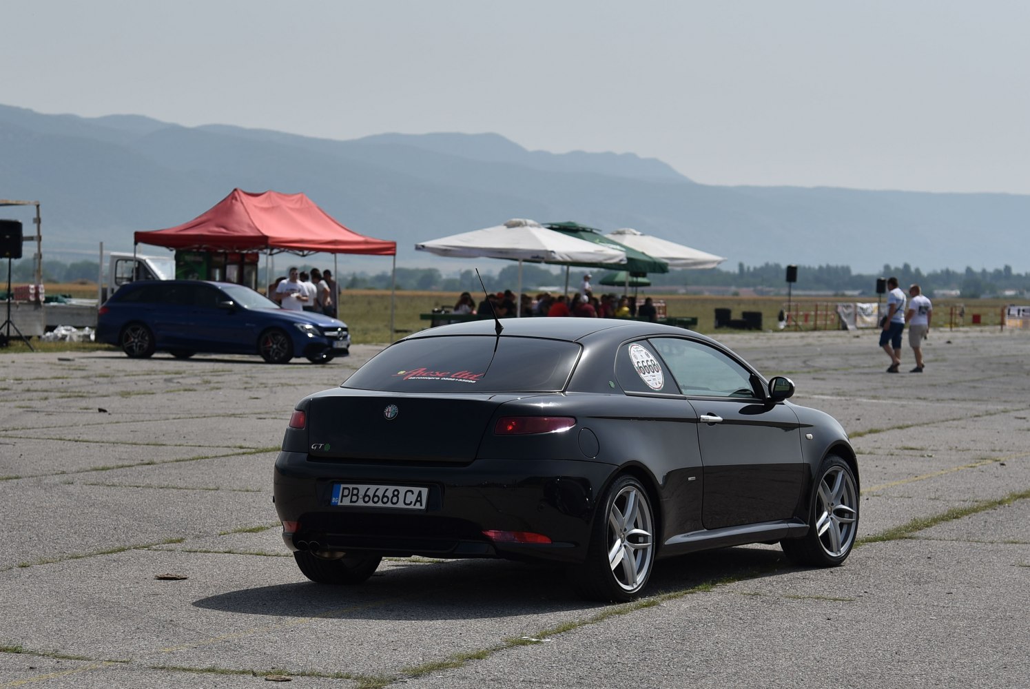 Rear angled view of black coupe with sporty alloy wheels and tinted windows.
