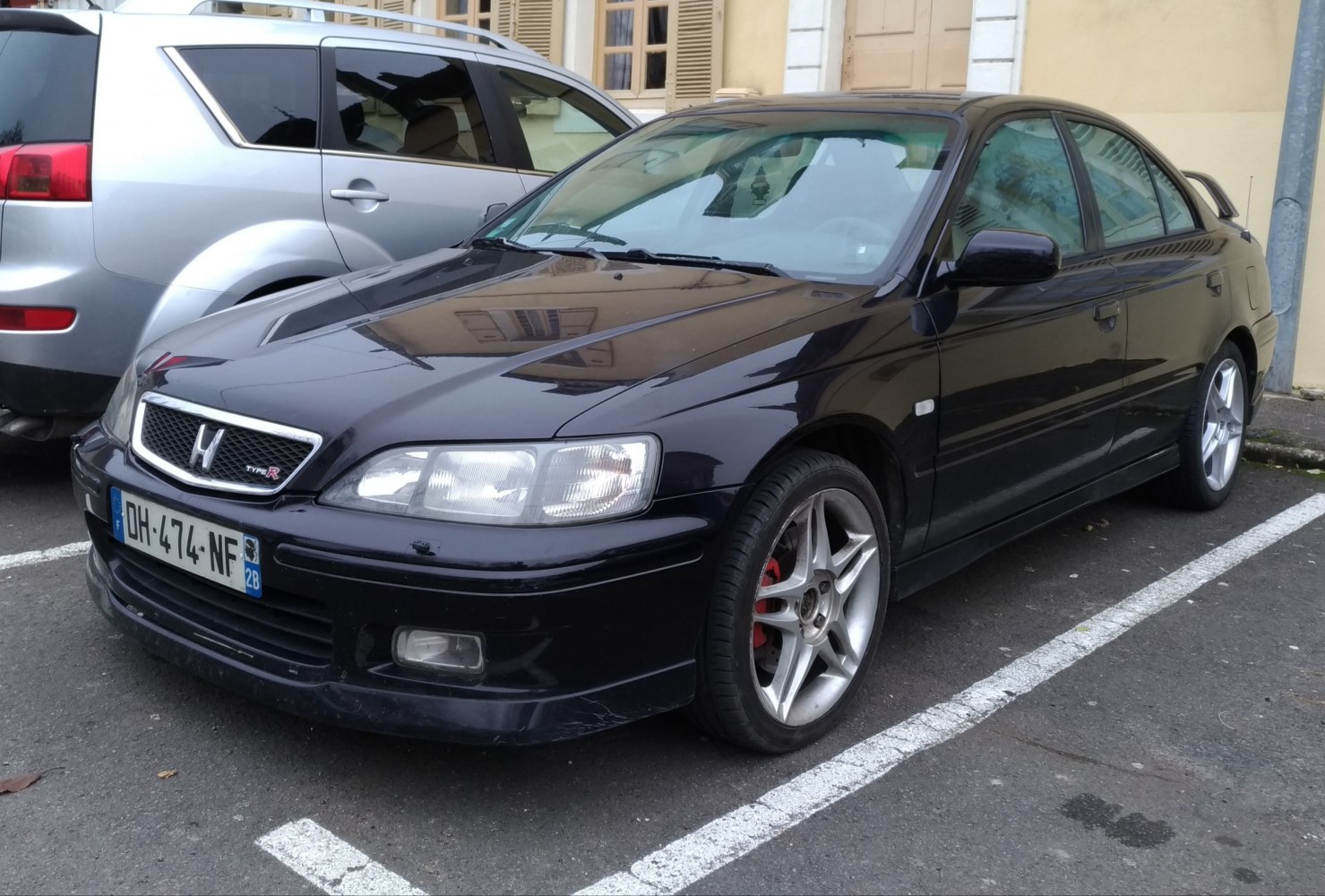Front-side view of sedan with alloy wheels and rear spoiler