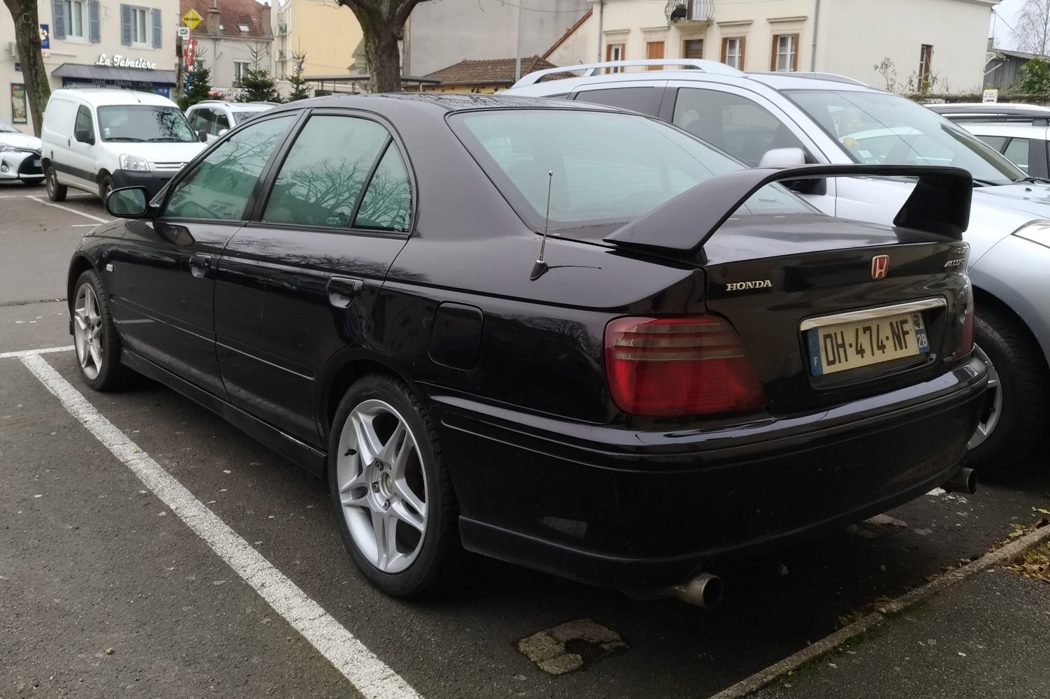 Rear-side view of black sedan with rear spoiler and alloy wheels.