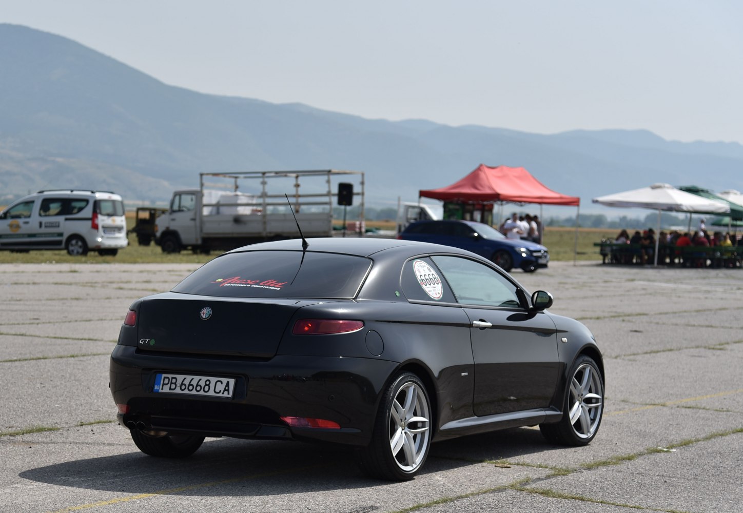 Black sports coupe rear three-quarter view with alloy wheels.