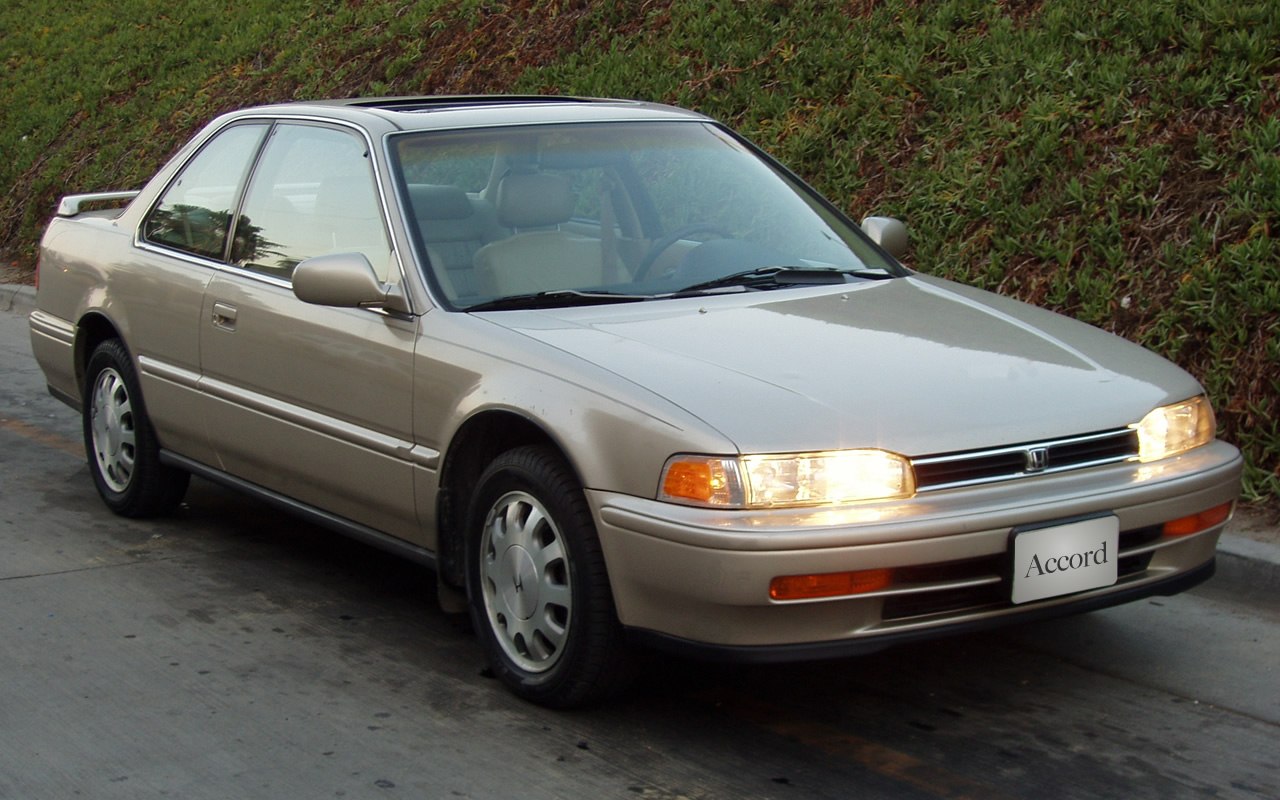 Front side view of a sporty coupe with headlights on and classic early 90s design