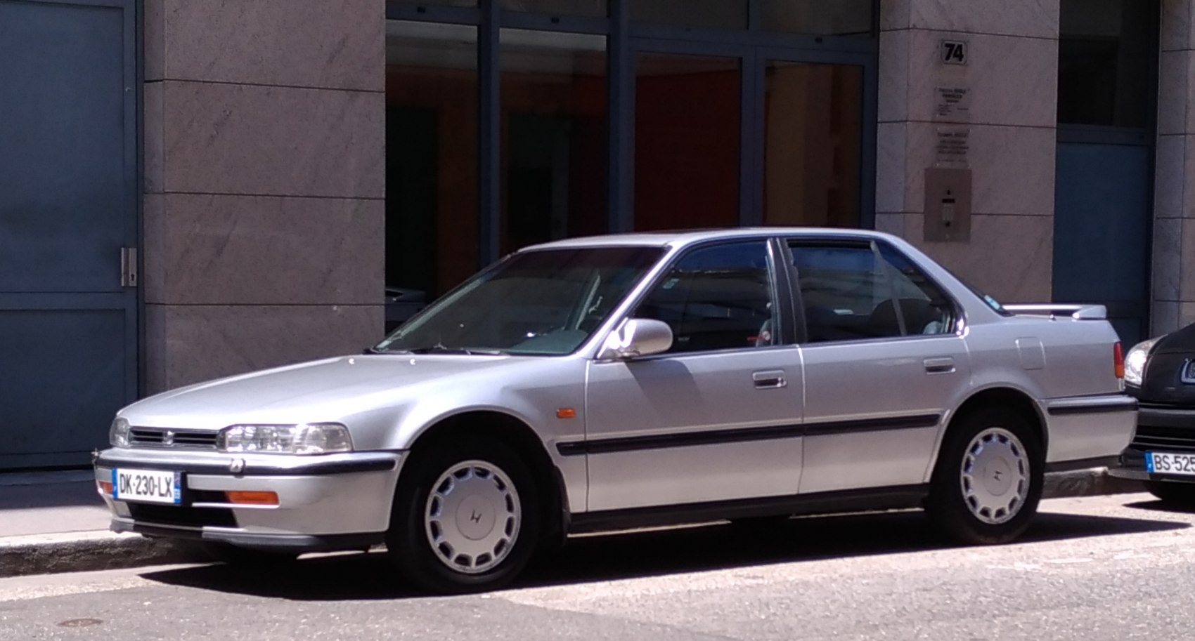 Silver four-door sedan with rear spoiler and alloy wheels parked on street