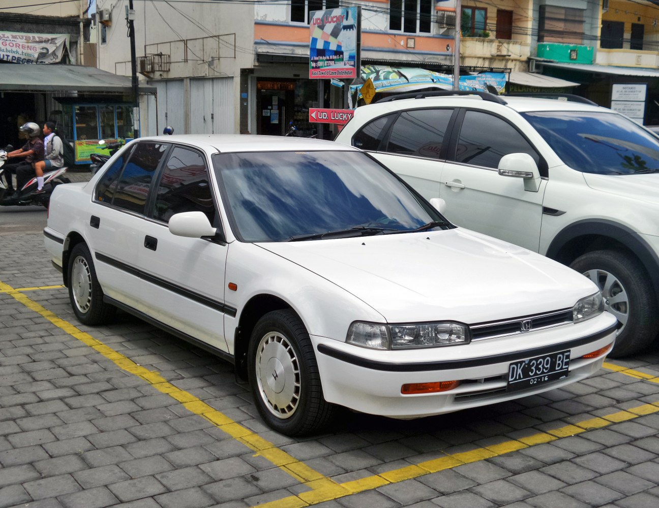 White 1990s sedan with rectangular headlights and tinted windows