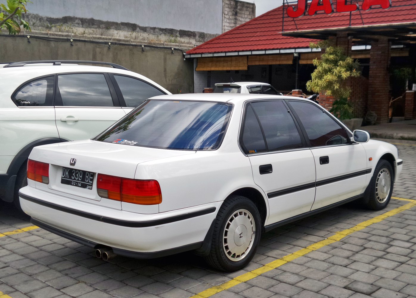 Rear angled view of classic 1990 sedan with distinctive tail lights and stock wheels