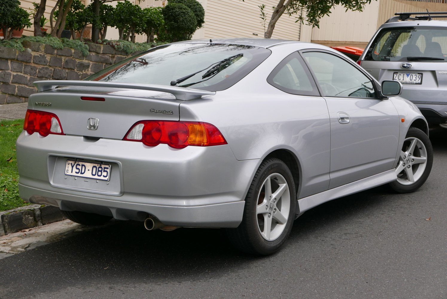 Rear side view of a silver coupé with spoiler and distinctive tail lights.