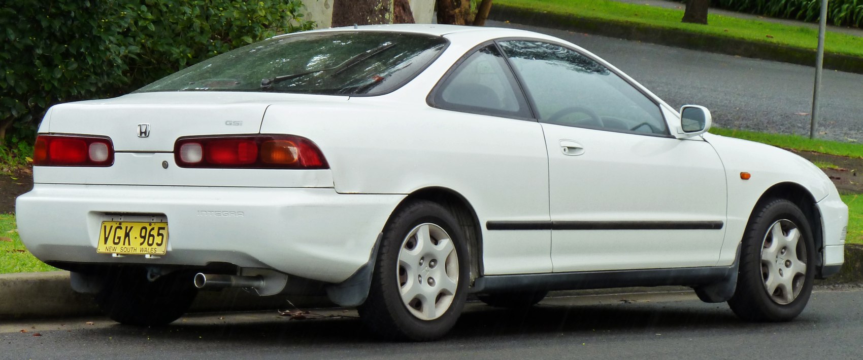 Rear side view of a white sporty coupe with unique tail lights and alloy wheels.