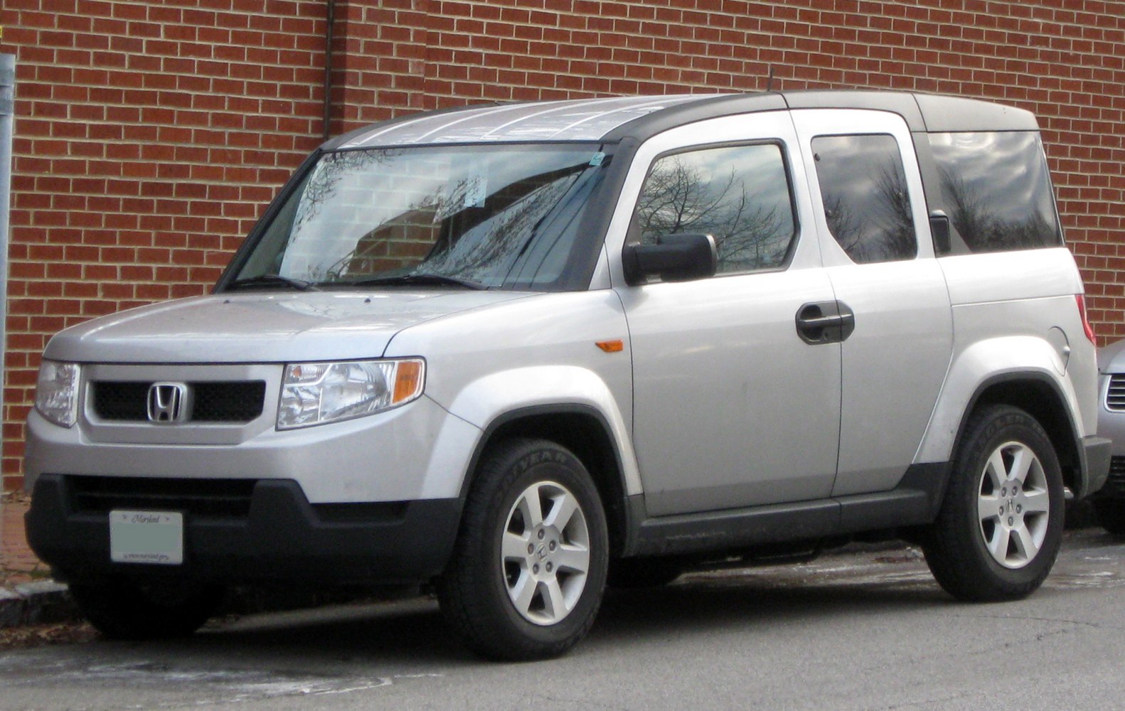 Front and side view of a boxy SUV with unique doors and silver paint