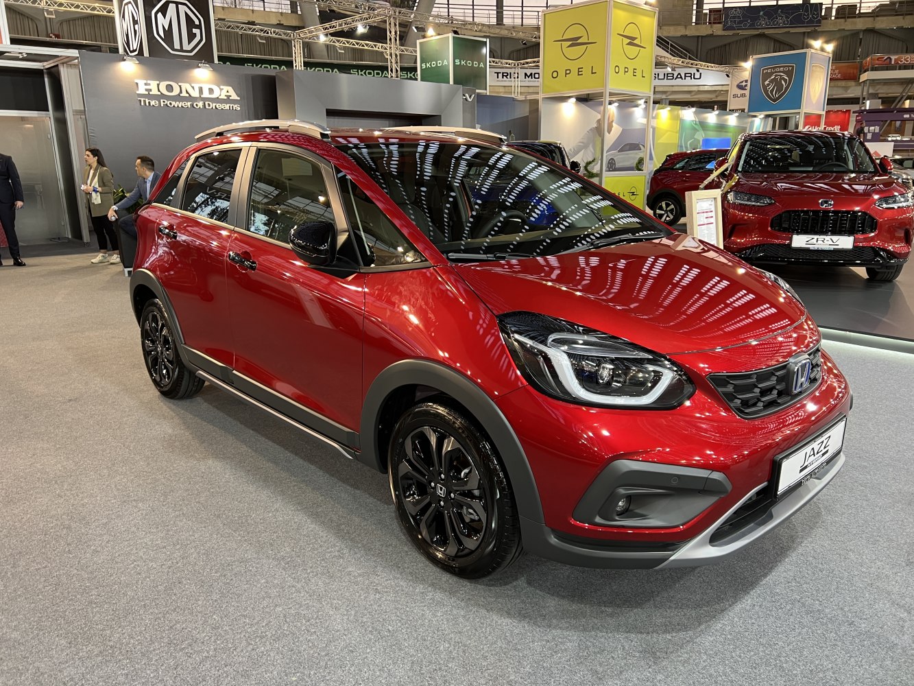 Front-side view of red hatchback with LED headlights and black wheels