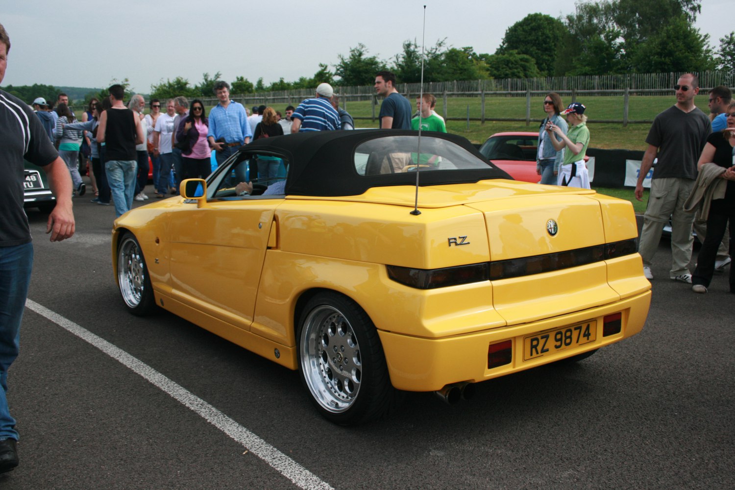 Yellow convertible with black soft top, rear view