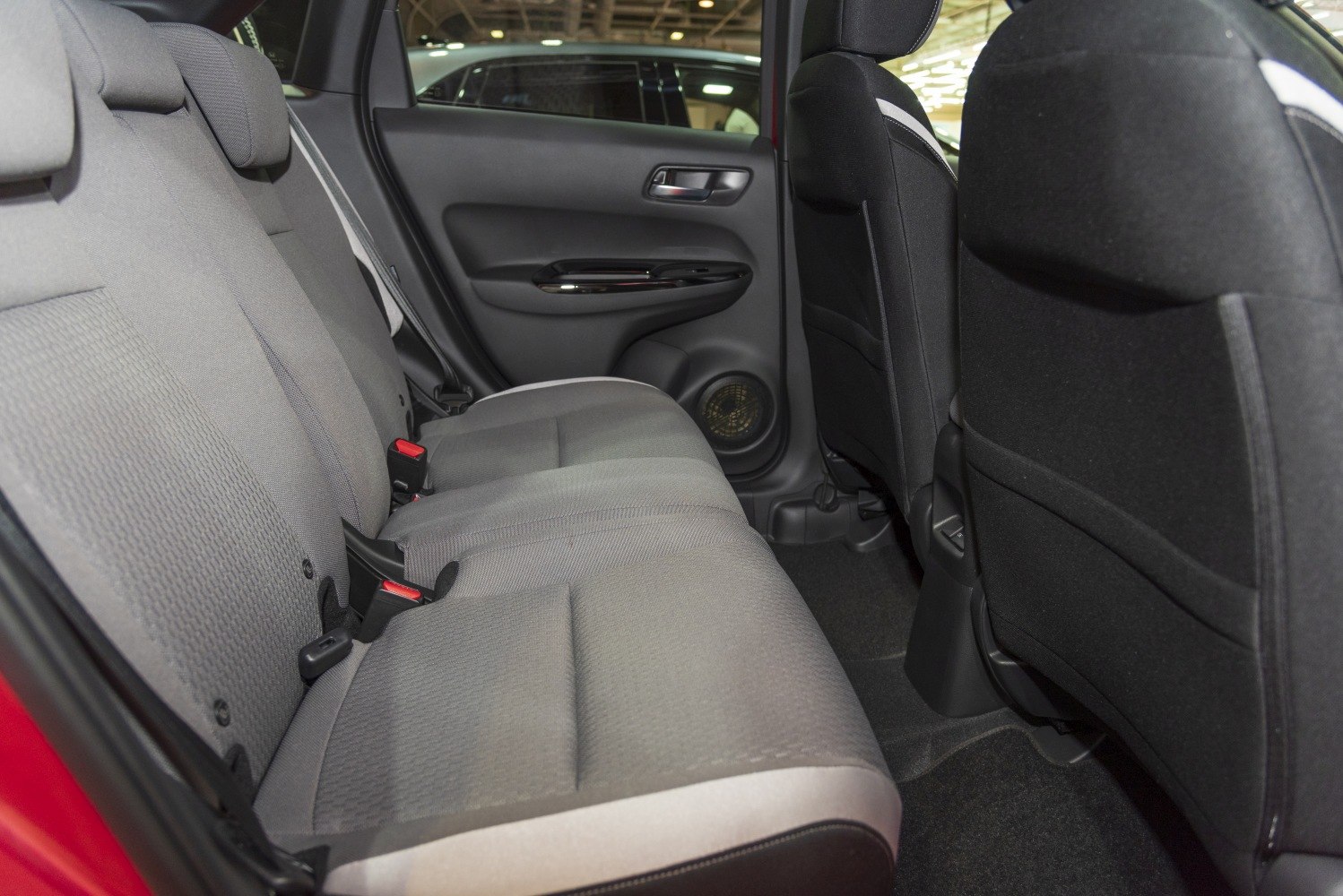 Rear fabric seats and door panel with speaker in compact car interior.